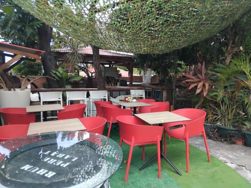 a restaurant with red chairs and a table and tables at Tidododesiles in Bouillante