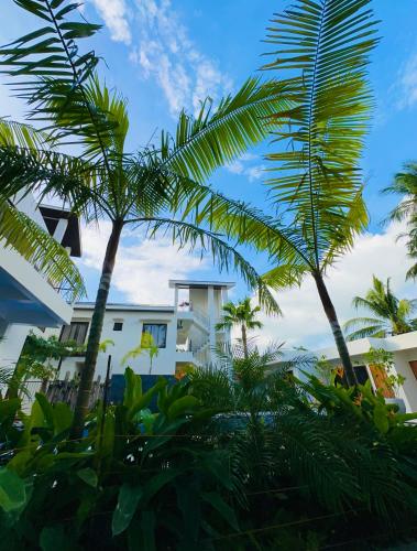 a white building with palm trees in front of it at La Vida Bonita Bed and Breakfast in San Vicente