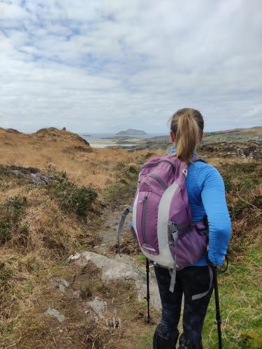 a woman with a backpack walking on a trail at Álaind Lodges, Sneem in Sneem