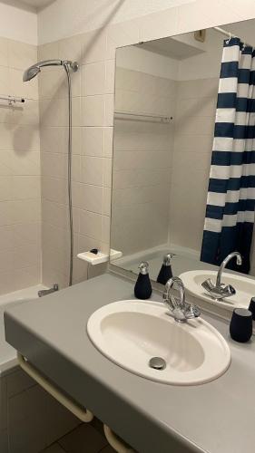 une salle de bain avec un lavabo et un miroir dans l'établissement L'échappé bleu, T2 vue imprenable sur la plage, à Andernos-les-Bains