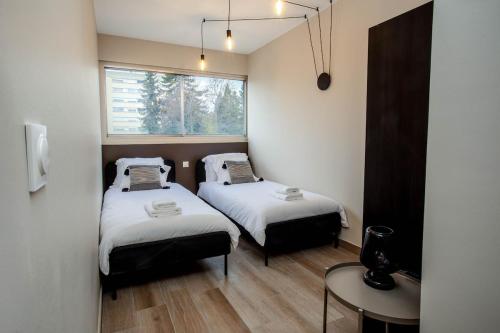 deux lits dans une petite pièce avec une fenêtre dans l'établissement Spacieux trois chambres proche GENEVE et ONU, à Ferney-Voltaire