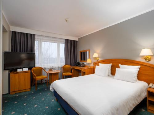 a hotel room with a bed and a flat screen tv at Mercure Czestochowa Centrum in Częstochowa
