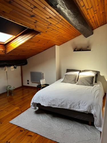une chambre avec un grand lit avec un plafond en bois dans l'établissement Spacieux et lumineux duplex arty au centre de Sète, à Sète