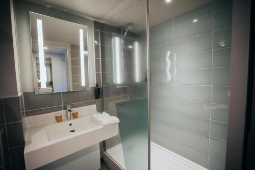 une salle de bain avec un lavabo et un miroir dans l'établissement ibis Styles Evry Lisses, Évry-Courcouronnes