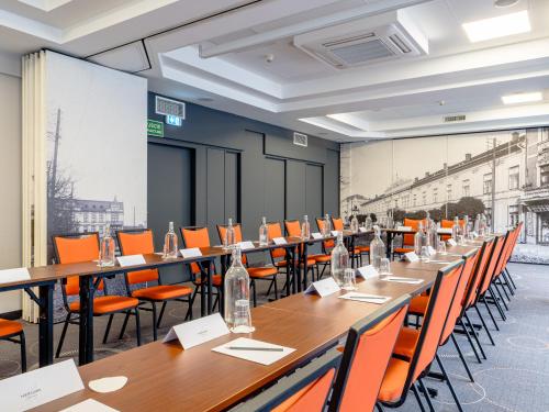 a conference room with long tables and orange chairs at Mercure Czestochowa Centrum in Częstochowa