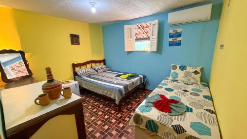 a room with two beds and a table and a bed at Casa Bantu - Vila Rosa in Vera Cruz de Itaparica
