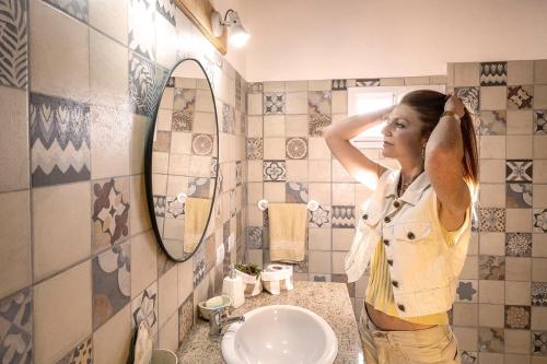 a woman standing in a bathroom looking in the mirror at La Calusita Huerta Grande in Huerta Grande