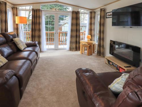 a living room with a leather couch and a television at Squirrels Snug in Windermere