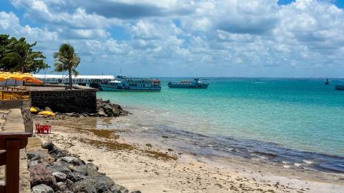 a beach with two boats in the water at Casa Bantu - Vila Rosa in Vera Cruz de Itaparica
