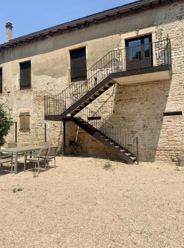 a wooden staircase next to a building with a table at Le Coup de Foudre Jardin - Spacieux in Sancé