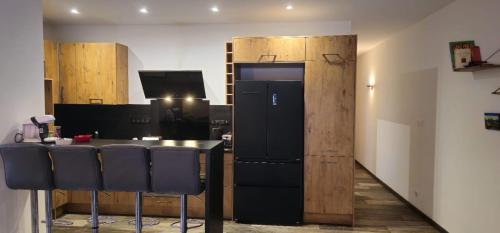 a kitchen with a counter with chairs and a refrigerator at Le Coup de Foudre Jardin - Spacieux in Sancé