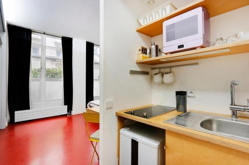 une petite cuisine avec un évier et une fenêtre dans l'établissement Studio Louvre Opera, à Paris