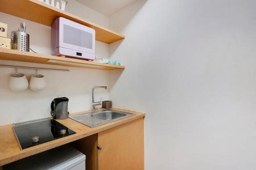 une petite cuisine avec un évier et un micro-ondes dans l'établissement Studio Louvre Opera, à Paris