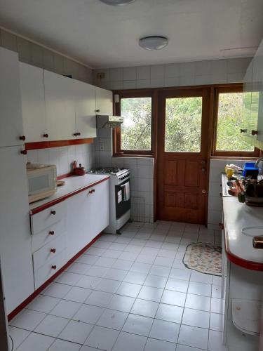 une cuisine avec des armoires blanches et un four à plaques de cuisson dans l'établissement Casa orilla de playa pucón, à Pucón