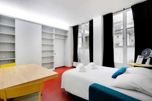 une chambre avec un lit, un bureau et des fenêtres dans l'établissement Studio Louvre Opera, à Paris