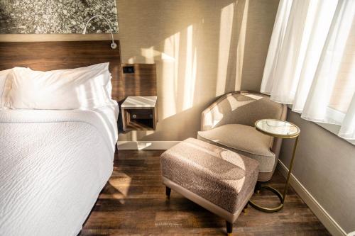 a bedroom with a bed and a chair and window at Old Orchard Inn in Wolfville