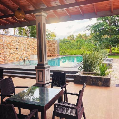 a patio with a table and chairs and a pool at Sunset Villa in Waskaduwa