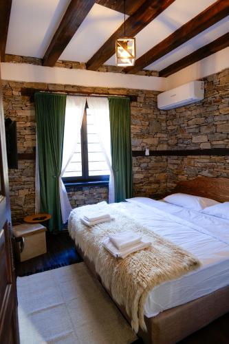 a bedroom with a large bed with green curtains at Трите къщи in Leshten