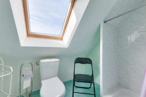 La salle de bains est pourvue d'une lucarne, de toilettes et d'une chaise. dans l'établissement À 500m de la plage, maison pour 6 avec jardin, à Sarzeau