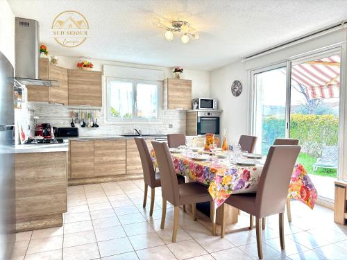 - une cuisine avec une table à manger et des chaises dans l'établissement Villa Les Lauriers -3 Chambres, Climatisation, Terrasse, Jardin, BBQ & Plancha- SUDSEJOURCONCIERGERIE, à Elne