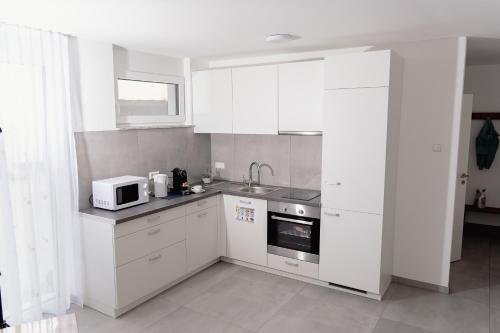 a kitchen with white cabinets and a microwave at GrenzApartments in Bietingen