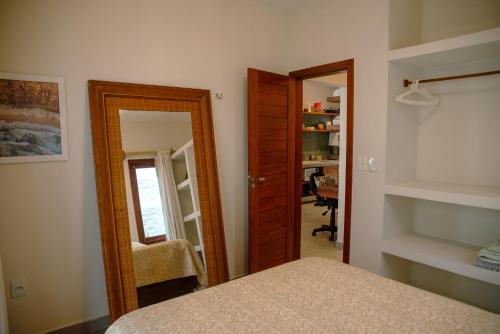a room with a mirror and a bed and a door at Chalé Compartilhado da Chica - Vila das Andorinhas in Pipa