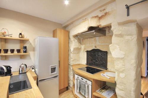 Il comprend une cuisine dotée d'un réfrigérateur blanc et d'un mur en pierre. dans l'établissement Studio cosy cœur Villeneuve-lez-Avignon, à Villeneuve-lès-Avignon