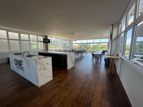 a large room with tables and chairs and windows at casa arejada em condomínio na praia de atlântida in Xangri-lá