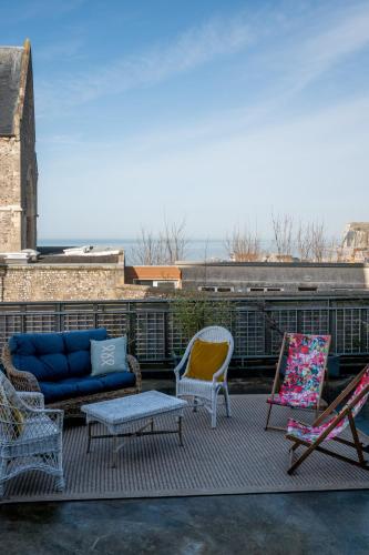un patio avec des chaises et un canapé sur le toit dans l'établissement La Maison Bleue, terrasses et vue panoramique mer, au Tréport
