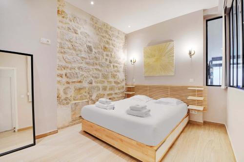 une chambre avec un lit blanc et un mur en pierre dans l'établissement Wonderful apartment - 2BR 8P - Aligre, à Paris