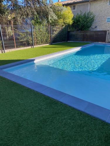 une piscine bleue avec de l'herbe verte dans l'établissement Les gîtes de mamie, à Saint-Martin-dʼArdèche