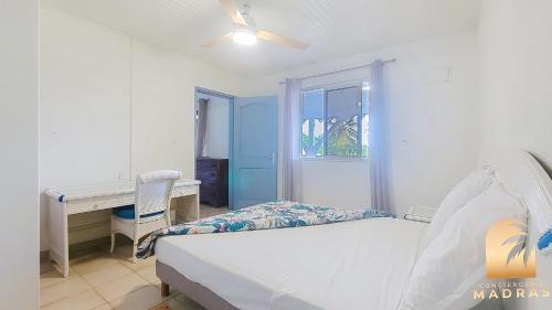 a bedroom with a bed and a desk and a window at Le refuge des 3Fs in Sainte-Marie