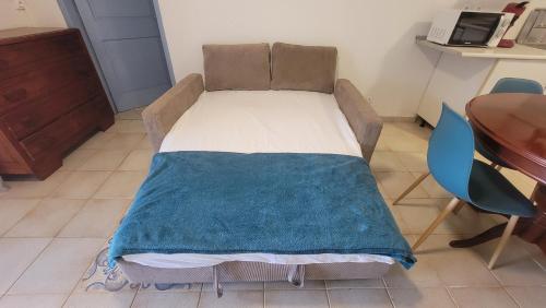 a bed with a blue blanket on it in a room at Le refuge des 3Fs in Sainte-Marie