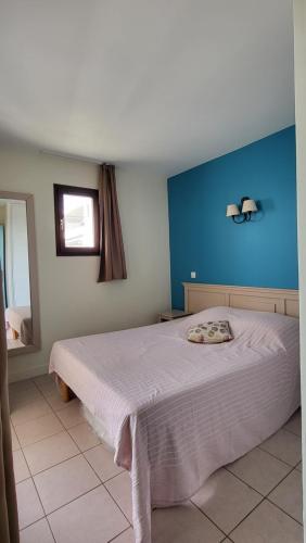 une chambre avec un grand lit avec un mur bleu dans l'établissement Le refuge côté mer, au Cap d'Agde