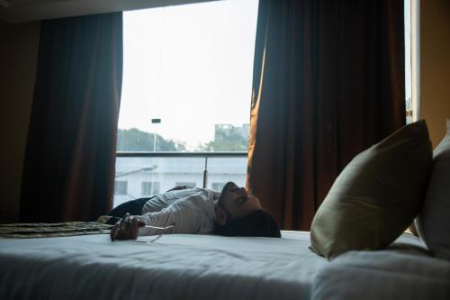 a woman laying on a bed next to a window at Park Eastern Hotel in Kolkata