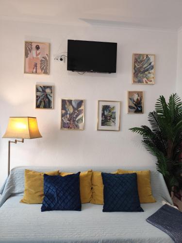 a living room with a couch and a tv on a wall at Stressfree Apartamento in Vila Nova de Milfontes