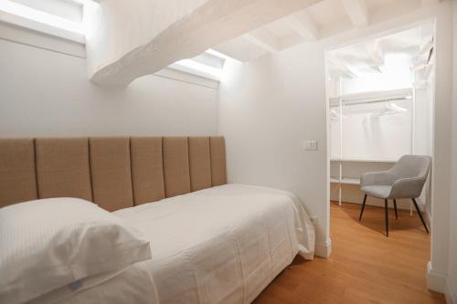 a white bedroom with a bed and a chair at Bargello Nine Luxury Suite in Florence