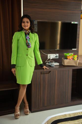 a woman in a green suit standing next to a desk at Park Eastern Hotel in Kolkata