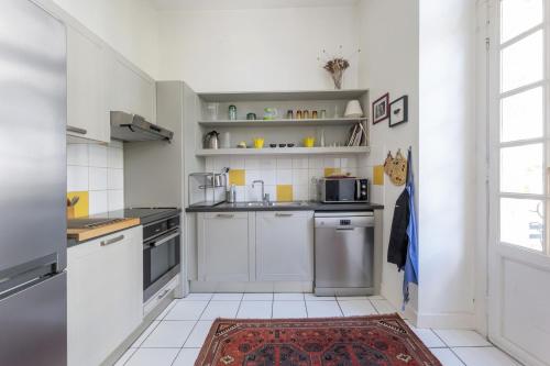 - une cuisine avec des armoires et des appareils blancs et un tapis dans l'établissement Porte Cailhau appartement 4 personnes, à Bordeaux