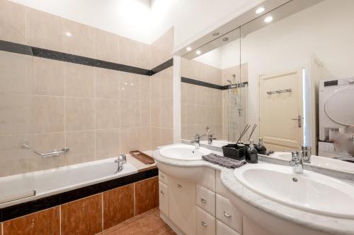 une salle de bain avec deux lavabos, une baignoire et un miroir dans l'établissement Porte Cailhau appartement 4 personnes, à Bordeaux