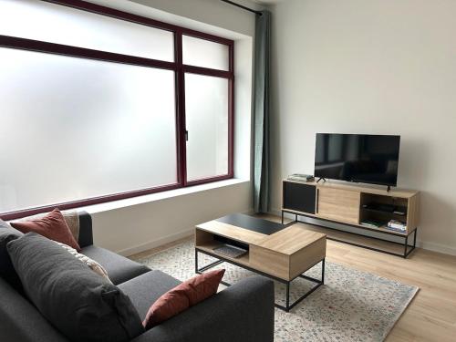 un salon avec un canapé et une télévision à écran plat dans l'établissement Les Remparts, centre-ville d'Hennebont, à Hennebont