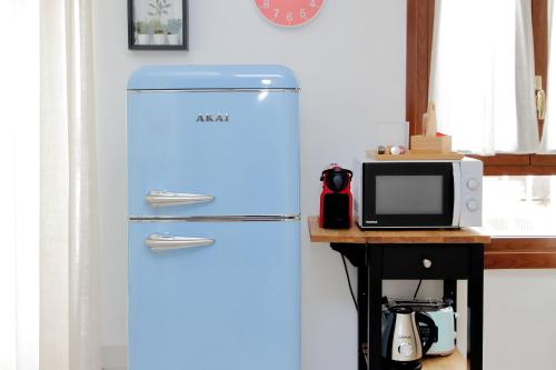 a blue refrigerator in a kitchen next to a microwave at Centro storico - ottimi collegamenti per Roma e APT in Fiumicino