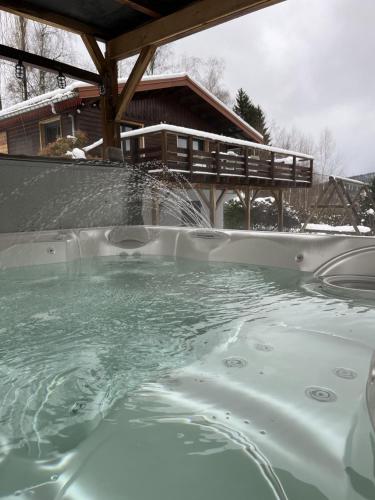 un bain à remous avec une fontaine en face d'une maison dans l'établissement Chalet Le Clefcy - Vosges - Spa - Proche Gérardmer, à Ban-sur-Meurthe-Clefcy