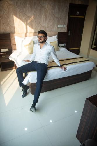 a man sitting on top of a bed at Park Eastern Hotel in Kolkata
