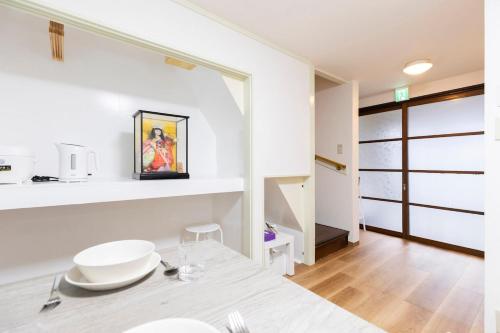 a kitchen with white walls and a dining room with a table at Forest Guest House Shinjuku city center in Tokyo