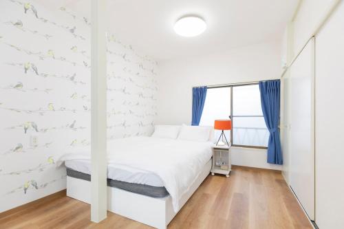 a white bedroom with a bed and a window at Forest Guest House Shinjuku city center in Tokyo