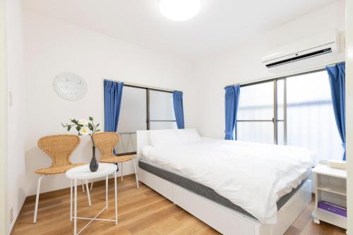 a white bedroom with a bed and two chairs at Forest Guest House Shinjuku city center in Tokyo