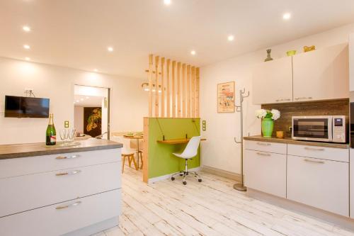 une cuisine avec des armoires blanches et une table avec un micro-ondes dans l'établissement Le Mont'aide - Bayeux - 3 lits - Accessible PMR, à Saint-Martin-des-Entrées