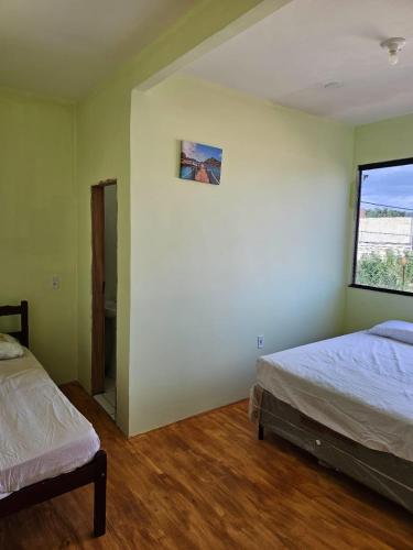 een slaapkamer met twee bedden en een raam bij Casa Mandacaru in Ubajara