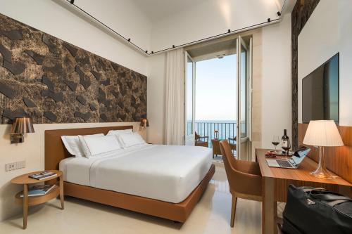 a hotel room with a bed and a desk with a laptop at Maniace Boutique Hotel Ortigia | UNA Esperienze in Siracusa